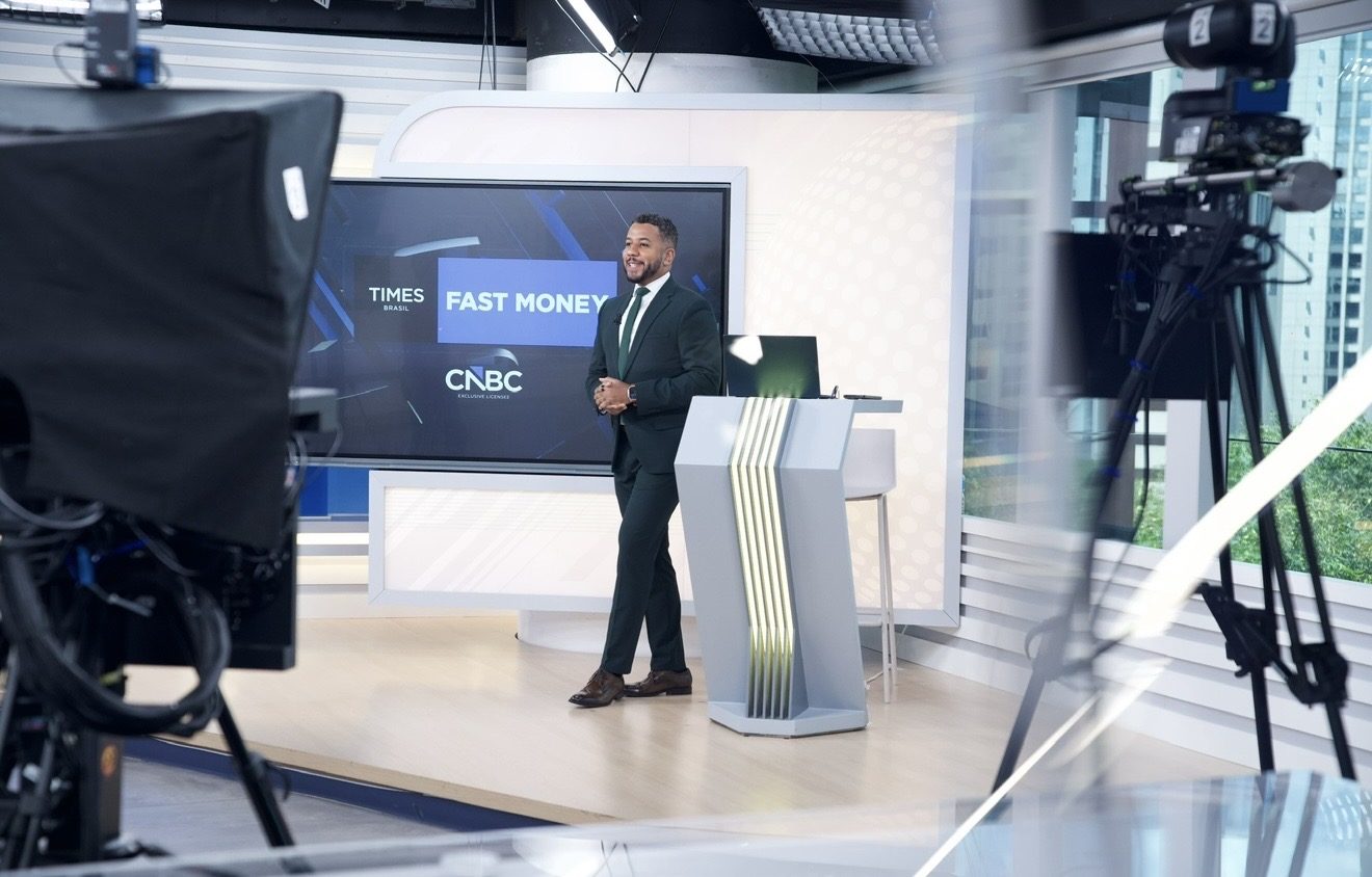 Renan de Souza na redação com o logotipo da CNBC ao fundo